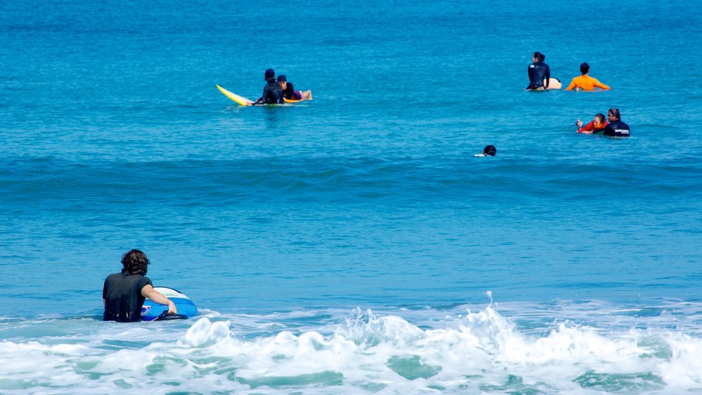 Praia de Legian caracterizando ondas e surfe assim como um grande grupo de pessoas