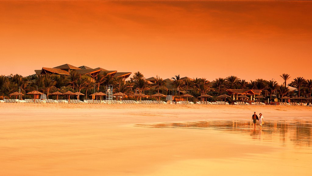 Praia e Parque Jumeira caracterizando um hotel de luxo ou resort, uma praia de areia e um pôr do sol