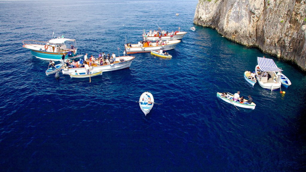 Blue Grotto mostrando botes y costa escarpada y también un gran grupo de personas