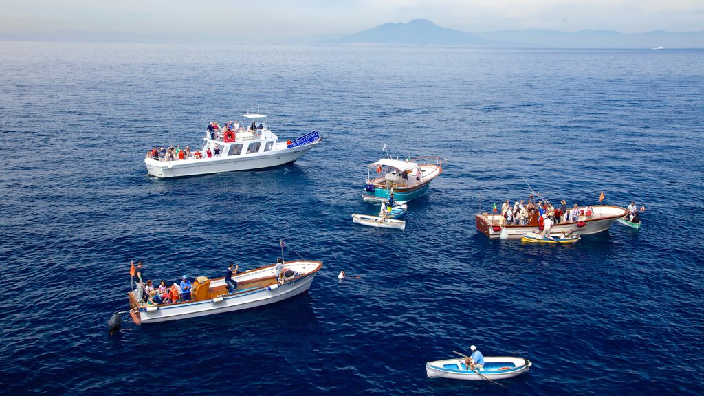 Blue Grotto ofreciendo vistas generales de la costa y paseos en lancha y también un gran grupo de personas