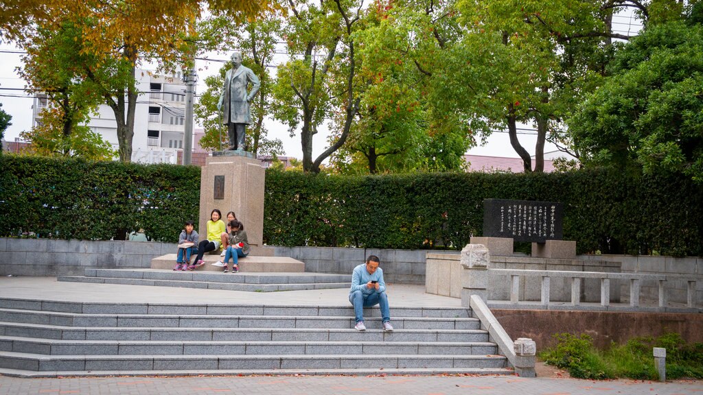 Gyosen Park which includes a statue or sculpture and a garden as well as an individual male