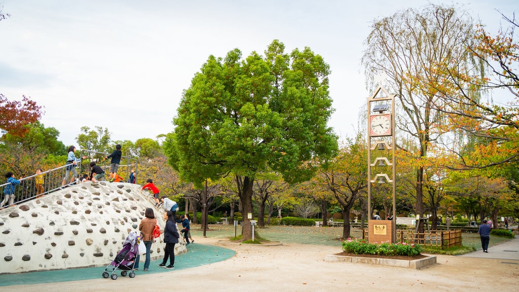 Parque Gyosen ofreciendo jardín y un patio de juegos y también una familia