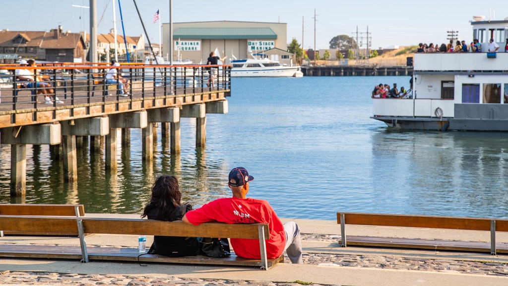 Jack London Square ofreciendo una bahía o un puerto y también una pareja