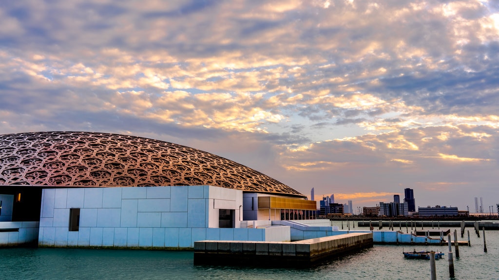 Louvre Abu Dhabi que incluye arquitectura moderna, vista general a la costa y un atardecer