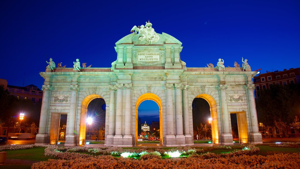 Puerta de Alcalá ofreciendo escenas nocturnas, un monumento y flores