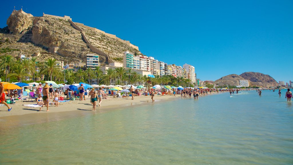 Postiguet Beach showing a coastal town, a sandy beach and swimming