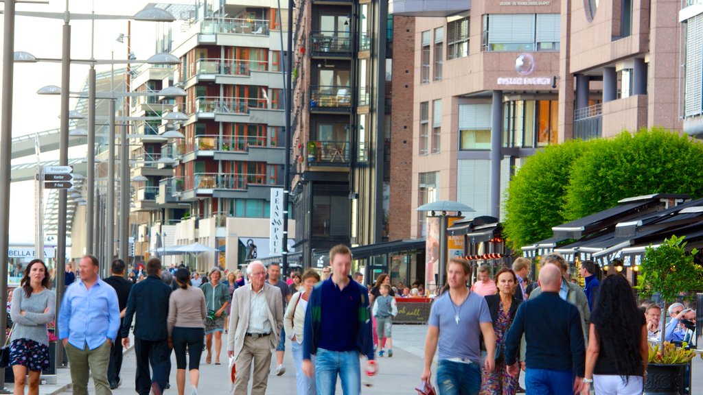 Aker Brygge que inclui uma cidade e cenas de rua assim como um grande grupo de pessoas