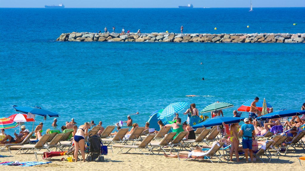 Barcelona som viser en sandstrand såvel som en stor gruppe mennesker