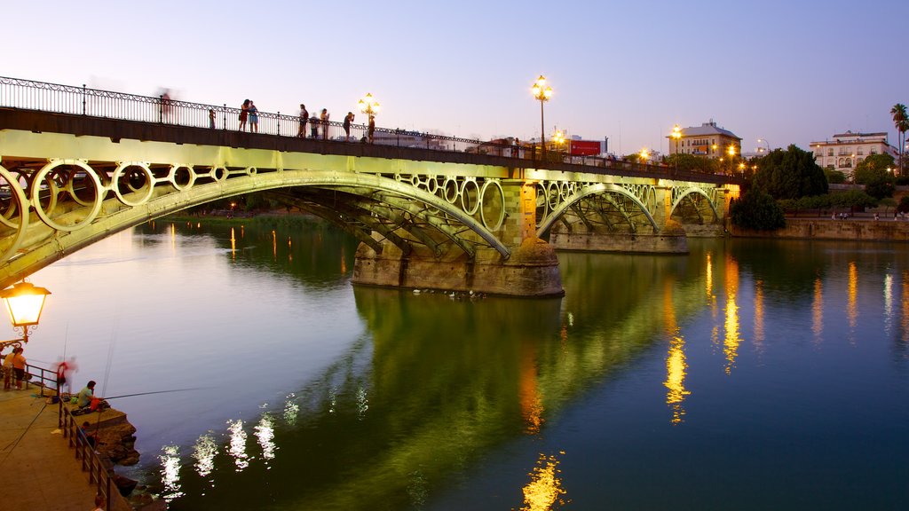 Puente de Triana mostrando un puente, un río o arroyo y escenas de noche