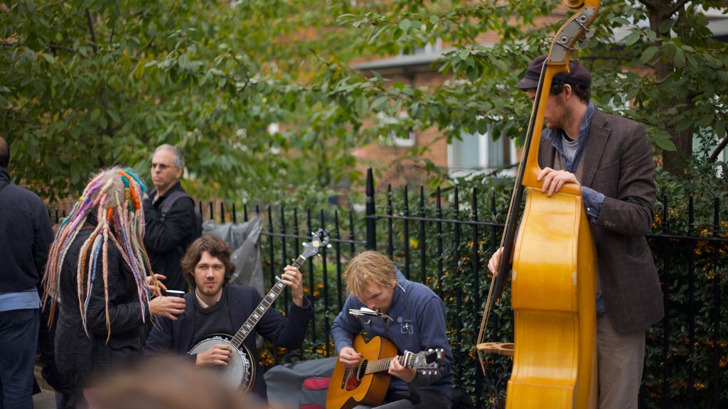 Notting Hill showing street performance and a garden as well as a small group of people