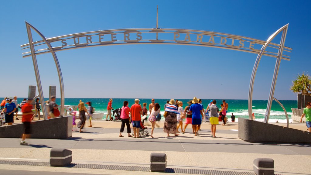 Surfers Paradise Beach which includes signage and a sandy beach as well as a large group of people