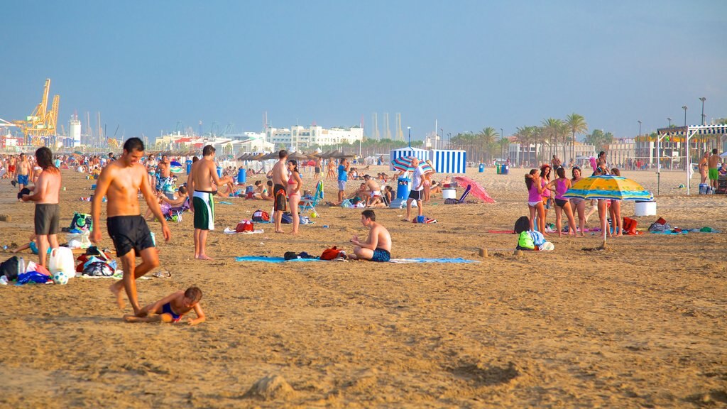 Malvarrosa Beach which includes a coastal town and a beach as well as a large group of people