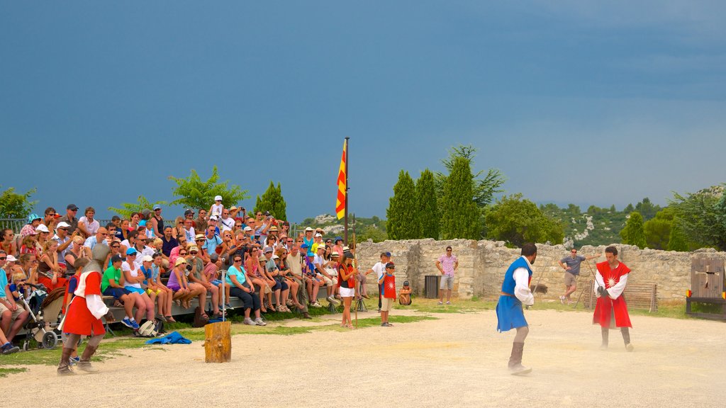 Chateau des Baux featuring performance art and a castle as well as a large group of people