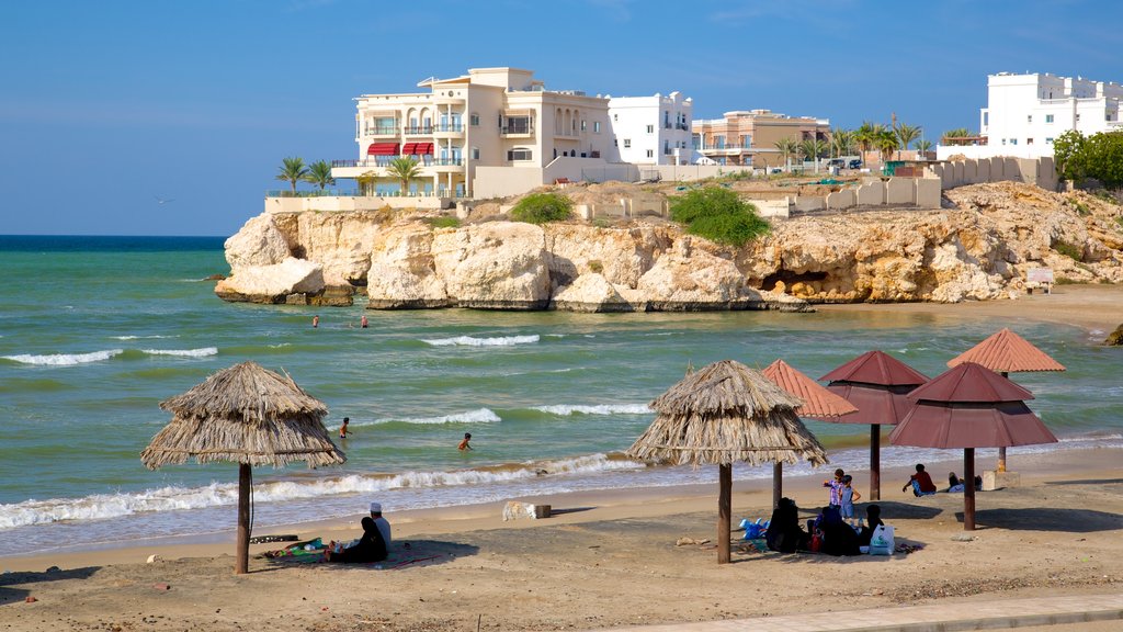 Shatti Al Qurum featuring a sandy beach, a coastal town and rocky coastline