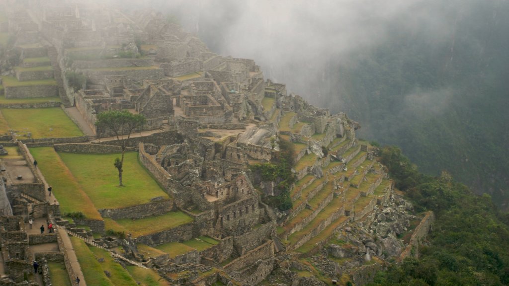 Machu Picchu featuring building ruins, mountains and mist or fog