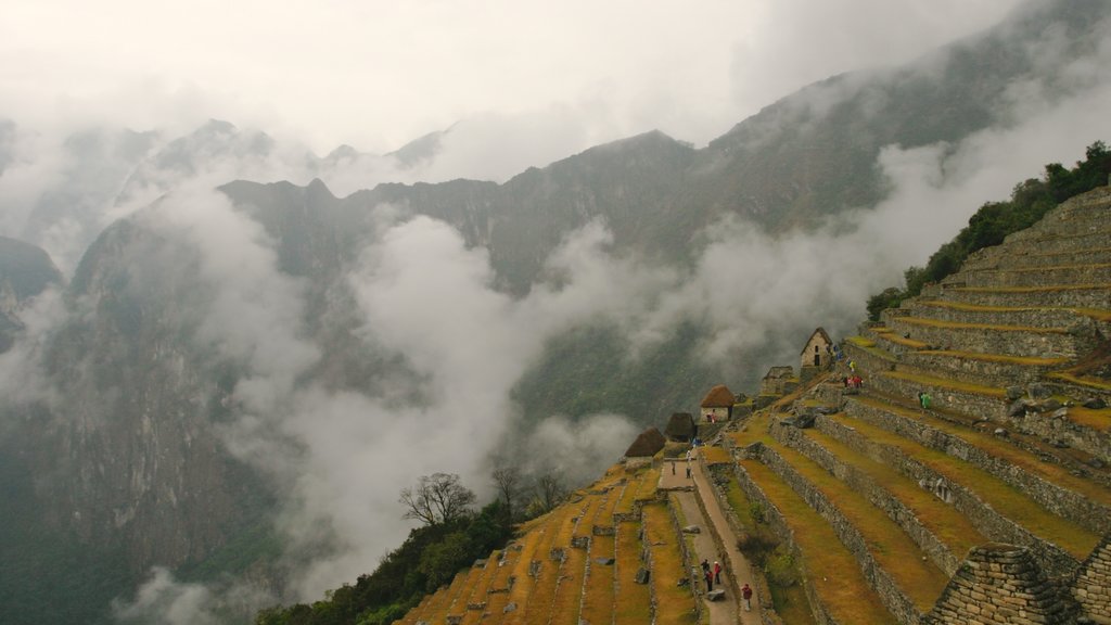 Machu Picchu showing a ruin, mist or fog and a small town or village