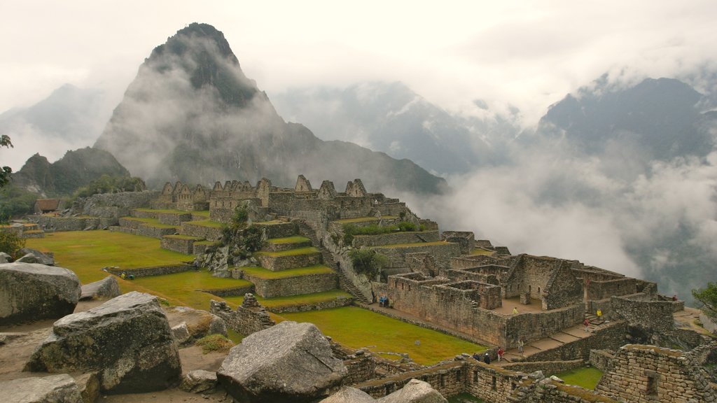 Machu Picchu ofreciendo ruinas de edificios, neblina o niebla y montañas