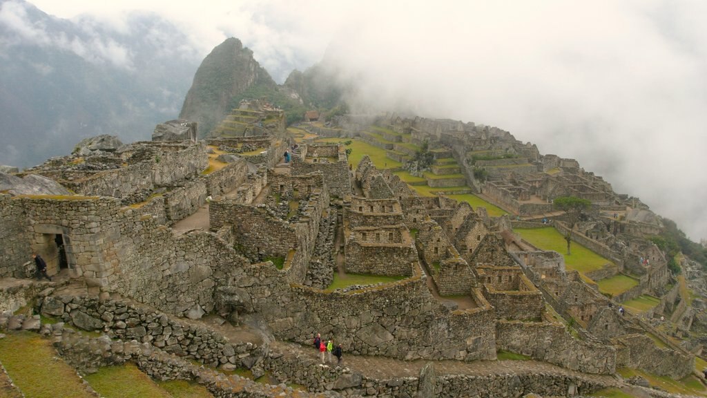 Machu Picchu mostrando niebla o neblina, montañas y una ruina