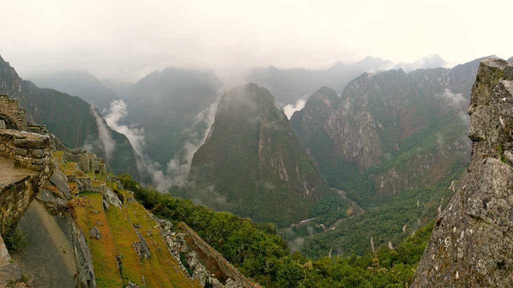 Machu Picchu featuring mountains, mist or fog and building ruins