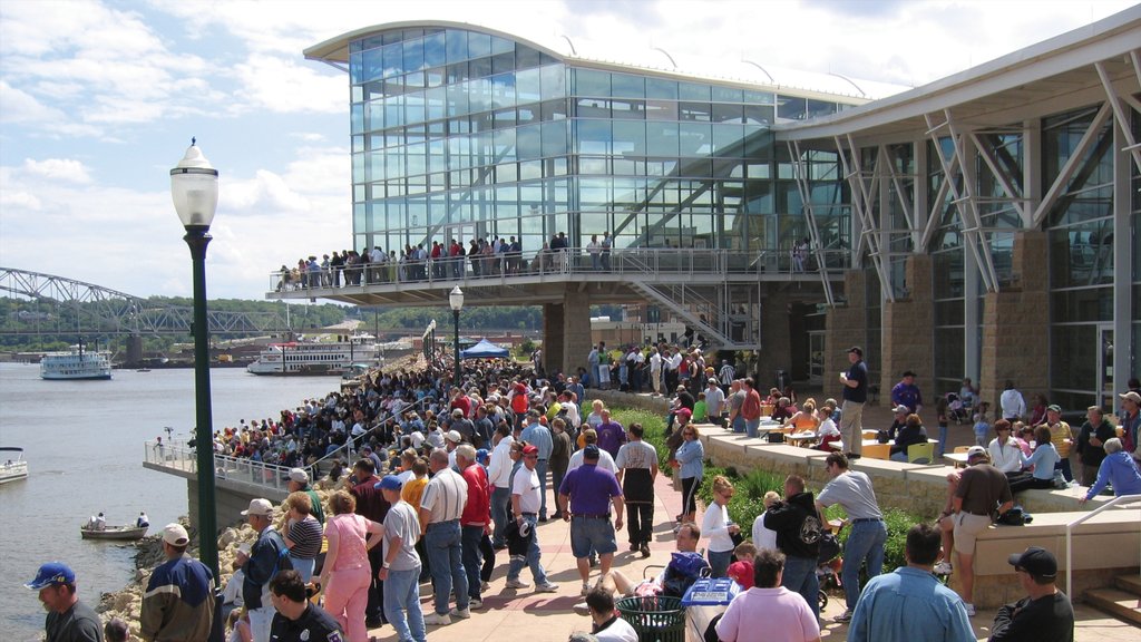 Downtown Dubuque featuring a river or creek and modern architecture as well as a large group of people