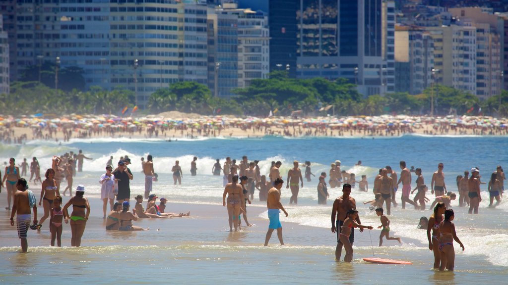 Copacabana Beach som viser svømning og en sandstrand såvel som en stor gruppe mennesker