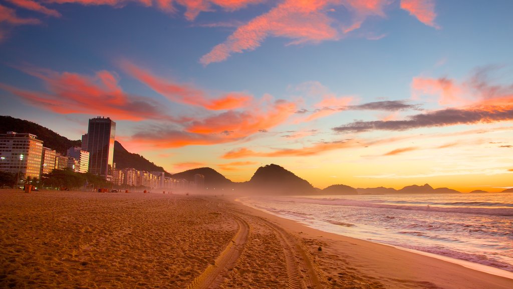 Playa de Copacabana que incluye un atardecer, una playa de arena y vista general a la costa