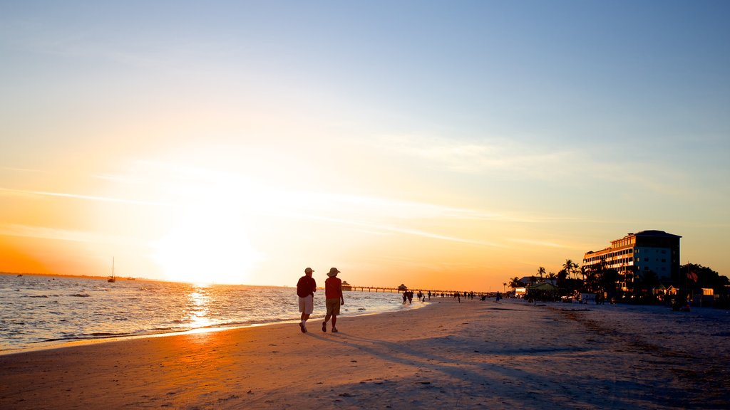 Fort Myers Beach which includes a sandy beach and a sunset as well as a small group of people