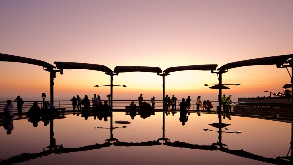 Lima que incluye un atardecer y un estanque y también un gran grupo de personas