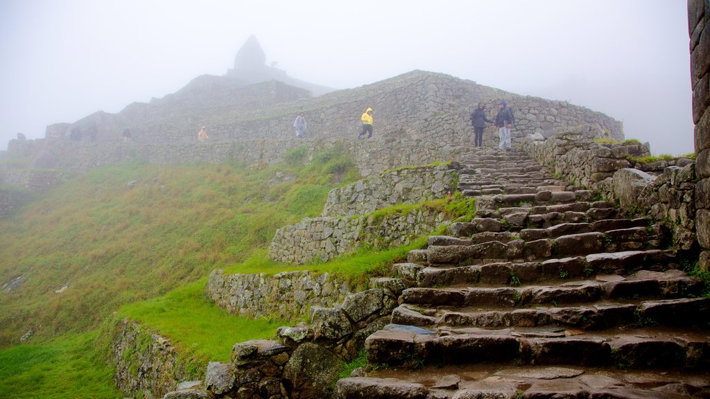 Machu Picchu featuring mist or fog, mountains and heritage architecture