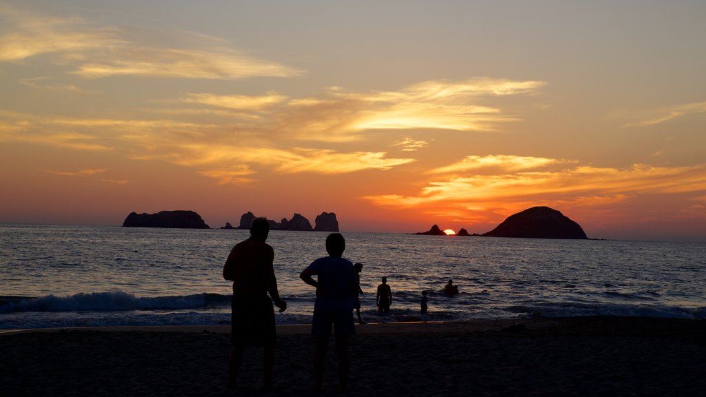 El Palmar Beach which includes a sunset and general coastal views as well as a large group of people