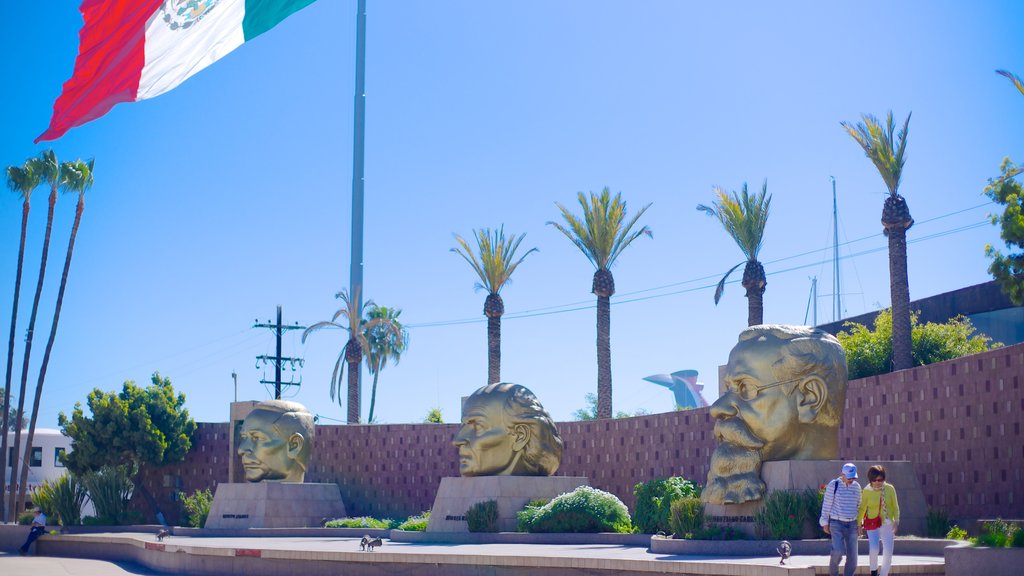 Ensenada mostrando una estatua o escultura y arte al aire libre y también una pareja