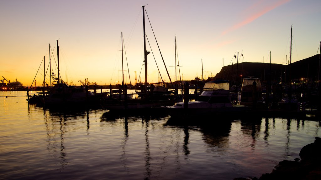 Ensenada ofreciendo un atardecer, botes y una ciudad costera