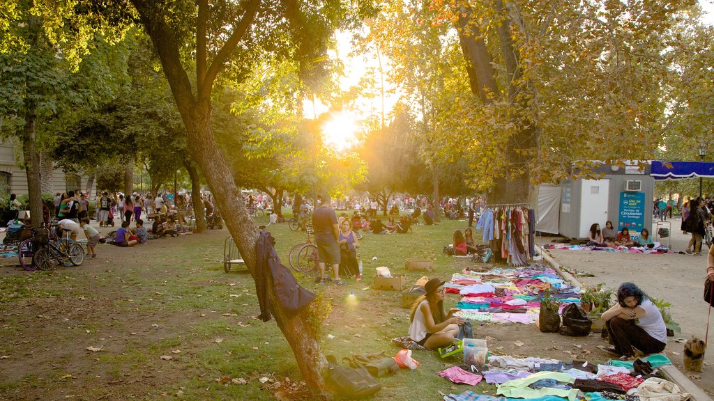 Parque Forestal que incluye una puesta de sol y un parque y también un gran grupo de personas