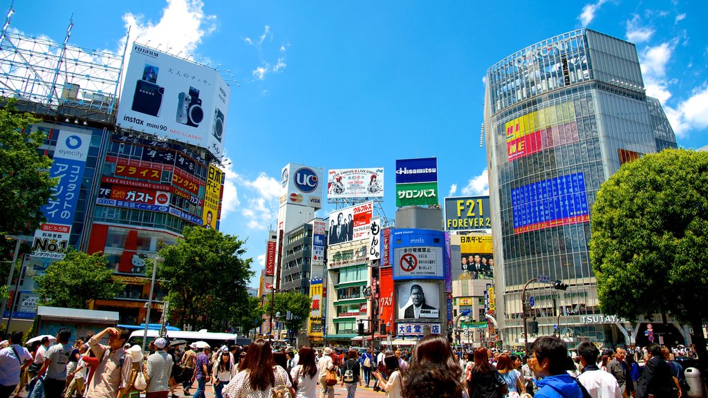 Cruce de Shibuya mostrando señalización, una ciudad y un edificio de gran altura