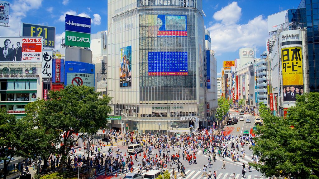 Cruce de Shibuya que incluye vistas de la ciudad, señalización y una ciudad