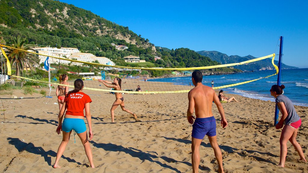 Playa de Pelekas ofreciendo una ciudad costera y una playa de arena y también un pequeño grupo de personas