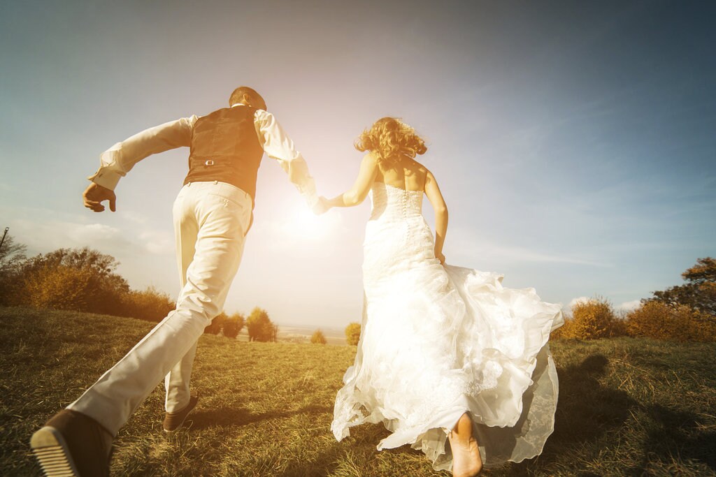 A bride and groom walking across a field