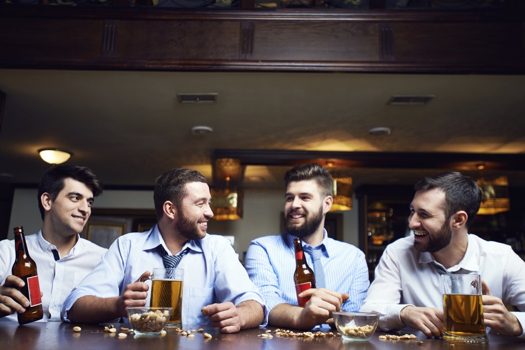 Group of men drinking beers and laughing in same outfits 