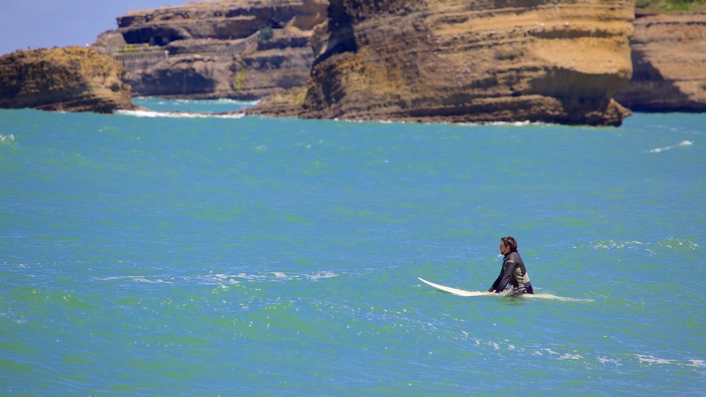 Grand Beach featuring surfing and rocky coastline as well as an individual male