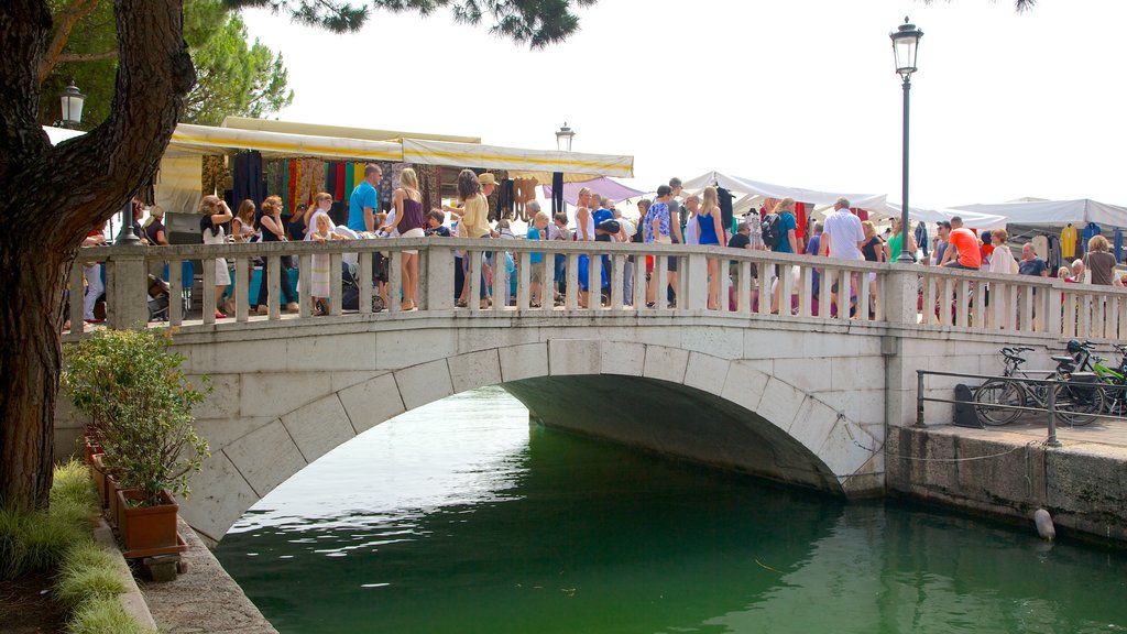 Desenzano del Garda showing a river or creek and a bridge as well as a large group of people