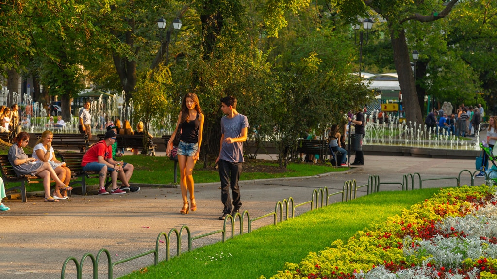 Plaza Príncipe Alejandro de Battenberg mostrando un jardín y flores y también un gran grupo de personas