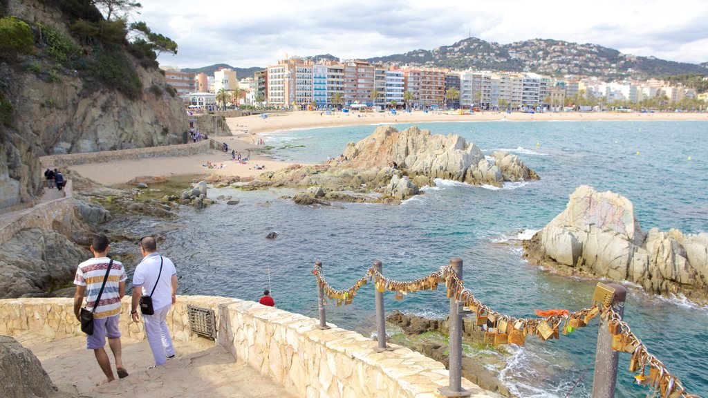 Lloret de Mar-stranden som inkluderar en stad och klippig kustlinje såväl som en liten grupp av människor