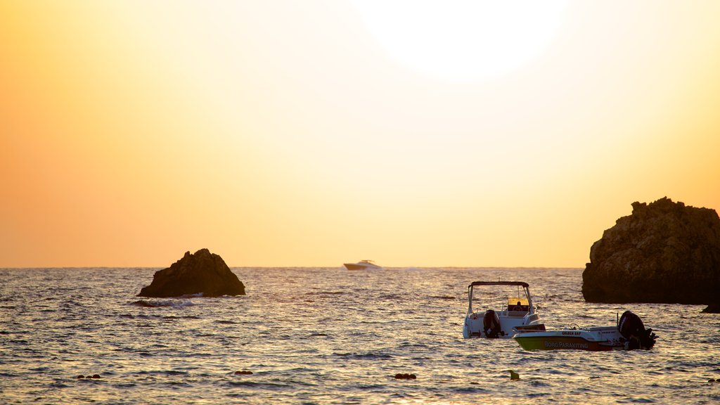 Playa de arena dorada ofreciendo una puesta de sol y costa rocosa