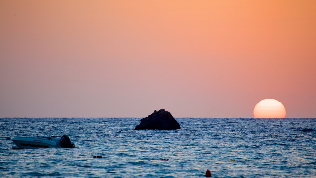 Praia Golden Sands mostrando um pôr do sol e litoral rochoso