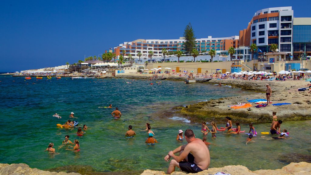 Bugibba Beach featuring rugged coastline, swimming and a coastal town