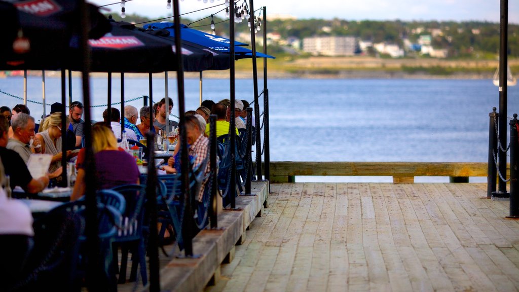 Halifax Waterfront Boardwalk featuring outdoor eating and a coastal town as well as a large group of people