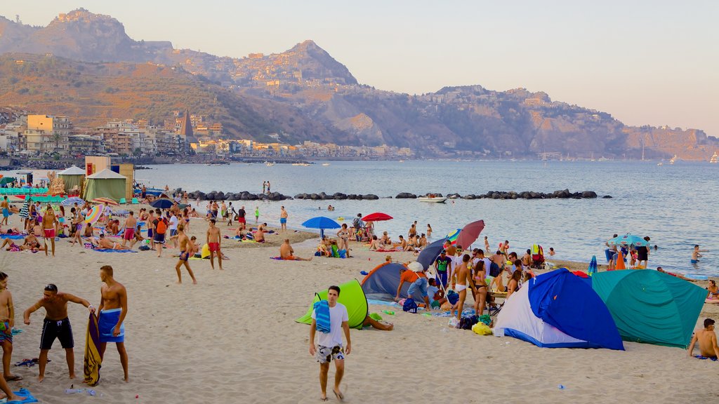 Giardini Naxos showing a sandy beach as well as a large group of people