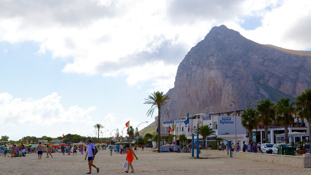 San Vito Lo Capo mostrando montanhas e uma praia de areia assim como um grande grupo de pessoas