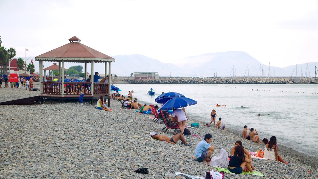 Punta Hermosa ofreciendo vistas generales de la costa y una playa de guijarros y también un gran grupo de personas