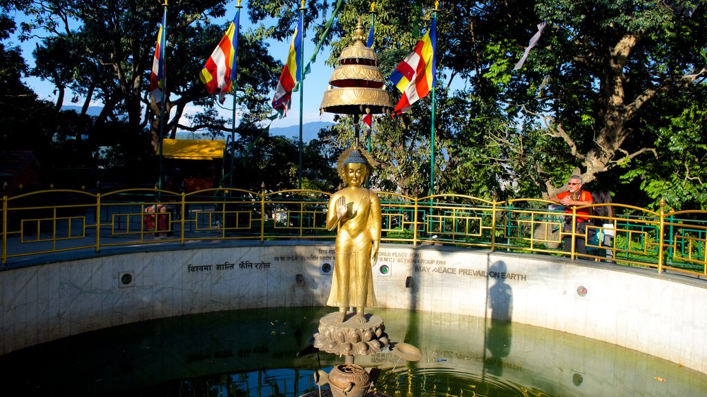 Swayambhunath showing a statue or sculpture, religious elements and a pond